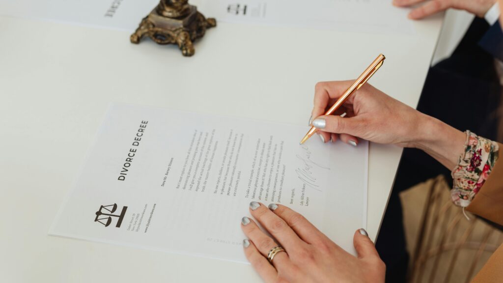 Close-up of hands signing a divorce decree document on a desk, showcasing legal process.